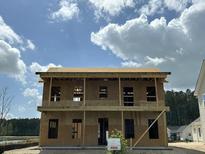 Unfinished two-story home featuring exposed plywood and a sign on the front lawn against a partly cloudy sky at 721 Blueway Ave, Summerville, SC 29486