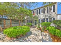 Charming two-story home with lush landscaping, stone patio, and classic black shutters offers inviting curb appeal at 73 Anson St, Charleston, SC 29401