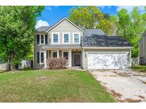 Charming two-story home with light green siding, a well-manicured lawn, and an attached two-car garage at 8499 Falling Leaf Ln, North Charleston, SC 29420