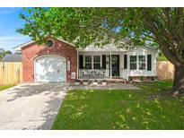 Charming single-story home featuring a brick facade and a cozy front porch, framed by mature trees and landscaping at 1306 Markley Ct, Moncks Corner, SC 29461