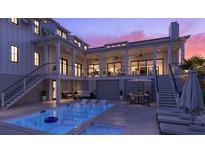 Inviting pool area with lounge chairs, outdoor seating, and well-lit porch overlooking the sparkling blue water at 1715 Middle St, Sullivans Island, SC 29482