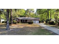 Charming brick home featuring an attached two-car garage, a well-manicured lawn, and mature trees at 3918 Dorsey Ave, North Charleston, SC 29405