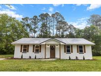 Charming renovated brick home featuring a metal roof, updated windows, and manicured front yard at 463 E Main Street, Harleyville, SC 29448