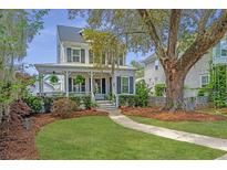 Charming two-story home with inviting front porch and landscaped yard, surrounded by mature trees and lush greenery at 5009 W Liberty Park Cir, North Charleston, SC 29405