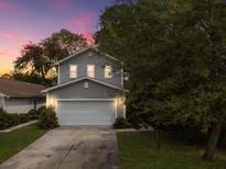 Charming two-story home features a gray exterior and a well-manicured front lawn at sunset at 8810 Gilston Ln, North Charleston, SC 29420