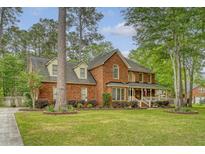 Charming two-story brick home with a spacious front yard, covered porch, and mature trees, offering classic curb appeal at 104 Leighton Ct, Summerville, SC 29485