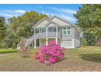 Charming coastal home featuring a garage, stairs to the covered porch, and colorful landscaping at 1224 Midvale Ave, Charleston, SC 29412