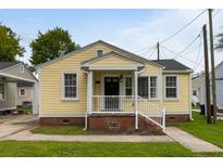 Charming yellow home featuring a cozy front porch with white railing and brick foundation at 3728 Tim St, North Charleston, SC 29405