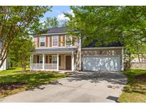 Charming two-story home with a welcoming front porch, landscaped yard, and attached two-car garage at 407 Burton Ave, Summerville, SC 29485