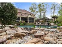 Inviting backyard pool area with rock waterfall, screened-in porch, and ample space for lounging and entertaining at 4217 Sawgrass Dr, Charleston, SC 29420