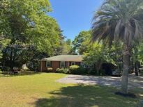 Charming one-story brick home with mature trees and a well-maintained front yard with gravel drive at 709 N Cedar St, Summerville, SC 29483