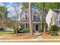 Charming two-story home featuring neutral siding, black shutters, a manicured lawn, and mature trees at 8961 N Red Maple Cir, Summerville, SC 29485