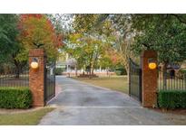 Gated driveway leading to charming home with beautiful landscaping and mature trees at 1068 Witherbee Rd, Moncks Corner, SC 29461