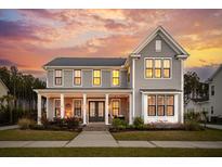Charming two-story home with a welcoming front porch and beautiful landscaping against a picturesque sunset sky at 184 Clearblue Loop, Summerville, SC 29486