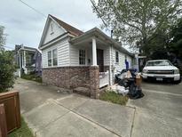 Charming single-story home with brick foundation, featuring a front porch and driveway at 227 & 229 Fishburne St, Charleston, SC 29403