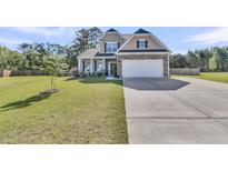 Charming two-story home featuring stone accents, a well-manicured lawn, and an attached two-car garage at 106 Lakelyn Rd, Moncks Corner, SC 29461