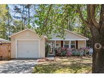 Charming single-story home with vinyl siding, an attached garage, and a well-maintained front yard with flowers at 1411 River Front Dr, Charleston, SC 29407