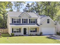 Charming two-story home featuring a welcoming front porch, well-maintained lawn, and attached garage, offering classic curb appeal at 150 Sugar Magnolia Way, Charleston, SC 29414