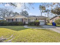 Charming brick home featuring a well-manicured lawn, attached garage, and mature landscaping at 1501 Birthright St, Charleston, SC 29407