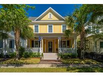 Charming yellow two-story home with a welcoming front porch and landscaped front yard with palm trees at 1700 Paradise Lake Dr, Mount Pleasant, SC 29464