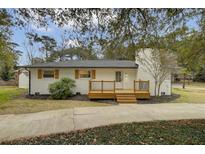 Charming home with a brick chimney and wood deck, complemented by lush landscaping and a welcoming entrance at 1897 Halo Ln, Charleston, SC 29407