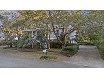 Charming two-story home with a landscaped front yard, mature trees, and a inviting driveway at 2 Wills Way, Isle of Palms, SC 29451