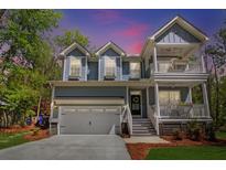 Charming home with a two-car garage, double porches, manicured lawn, and lush, mature landscaping at 2111 Nicholas David Path, Johns Island, SC 29455