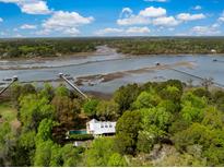 Aerial view of a beautiful house with a pool and surrounded by lush greenery and a waterfront at 3060 Bohicket Rd, Johns Island, SC 29455