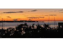 Scenic waterfront sunset view showing dramatic sky colors, calm waters, and distant city lights, creating a serene and picturesque scene at 330 Concord St # 4B, Charleston, SC 29401
