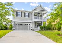 Charming home with a front porch, two-car garage, and a well-maintained lawn under a partly cloudy sky at 408 Branch Creek Trl, Summerville, SC 29483