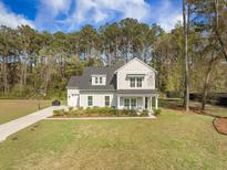 Charming two-story home features a well-manicured lawn, beautiful landscaping, and a welcoming front porch at 4332 John Hatch Dr, Johns Island, SC 29455
