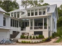 Stunning two-story home with white siding, black-framed windows, metal roof and a beautiful outdoor living space at 791 Hughes Rd, Johns Island, SC 29455