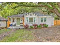 Charming white brick home with a quaint front porch and vibrant green door nestled beneath mature trees at 1188 Camden St, North Charleston, SC 29405