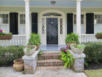 Charming home entrance with black door, decorative sidelights, brick steps, and lush potted plants at 141 Beaufain St, Charleston, SC 29401