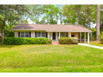 Charming single-story home with a well-maintained lawn, lush landscaping, and a covered carport at 1785 N Mayflower Dr, Charleston, SC 29412