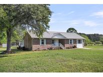 Charming brick home features a metal roof, tidy landscaping, and a spacious front yard at 217 Mini Farm Rd, Bonneau, SC 29431
