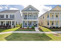 Charming two-story home with a double porch and inviting curb appeal set among green lawns on a sunny day at 2743 Calico Bass Ln, Johns Island, SC 29455