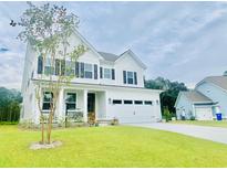 Charming two-story white home boasts a well-manicured lawn, black shutters and a two-car garage at 3025 Dewitt Ct, Hollywood, SC 29449