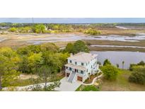 Stunning marshfront home with a metal roof, an inviting porch, and professional landscaping at 546 Towles Crossing Dr, Johns Island, SC 29455