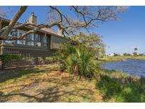 Beautiful home exterior with lagoon view and lush greenery on a sunny day with blue skies at 764 Summerwind Cir, Edisto Beach, SC 29438