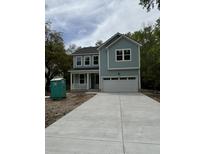Charming two-story home with light blue siding, a front porch, and a large driveway leading to a two-car garage at 971 Beehive Rd, Awendaw, SC 29429