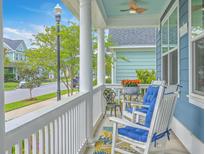 Inviting front porch features rocking chairs with blue cushions and a view of the neighborhood at 110 Angelica Ave, Summerville, SC 29483