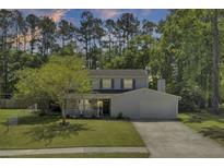 Charming two-story home with a well-manicured lawn, mature trees, and a welcoming front porch at 116 Trestlewood Dr, Summerville, SC 29486
