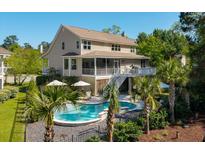Stunning backyard featuring a pool, palm trees, deck, screened porch, and lush landscaping, creating an inviting outdoor retreat at 1339 River Otter Court, Mount Pleasant, SC 29466
