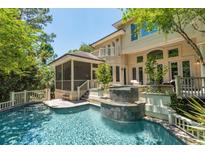 Beautiful backyard pool with waterfall feature and screened-in porch of this luxury home at 14 Royal Beach Dr, Kiawah Island, SC 29455