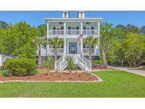 Inviting two-story white home featuring double porches, an American flag, and verdant landscaping at 1535 Capel St, Mount Pleasant, SC 29466