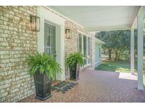 Inviting front porch with brick facade, decorative plants, and a cozy 