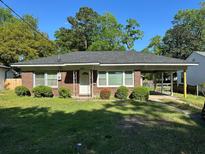 Charming brick home with a well-maintained lawn, covered parking, and neatly trimmed landscaping at 5458 Crown Ave, North Charleston, SC 29406