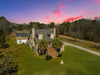 Charming exterior of a multi-story home with a lush green lawn and beautiful, clear colorful sky at sunset at 6440 St Anthony Dr, Hollywood, SC 29449