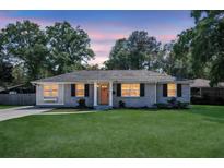 Charming brick home with a lush green lawn and inviting front porch with an orange colored front door at 733 Longfellow Rd, Charleston, SC 29407